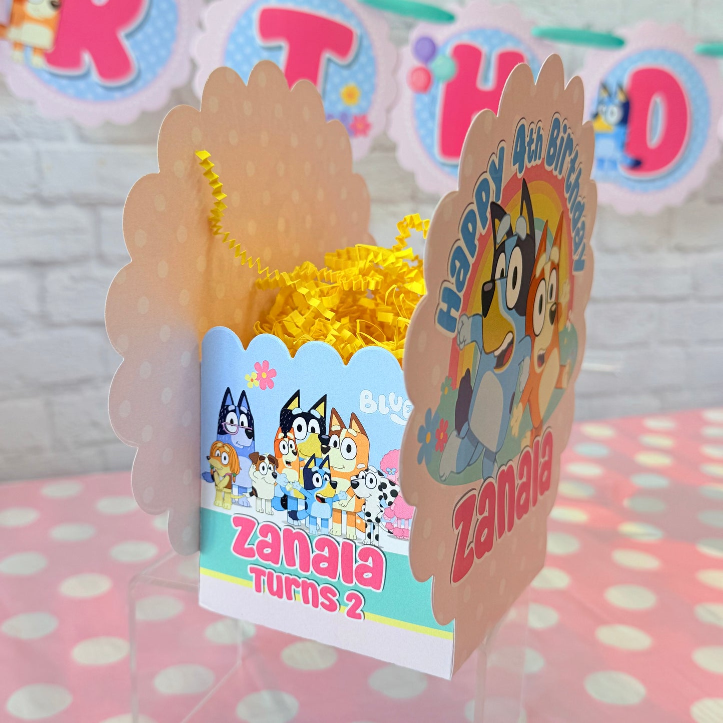 Personalized Bluey birthday party table centerpiece in pink color scheme with a rainbow and flowers for birthday girl