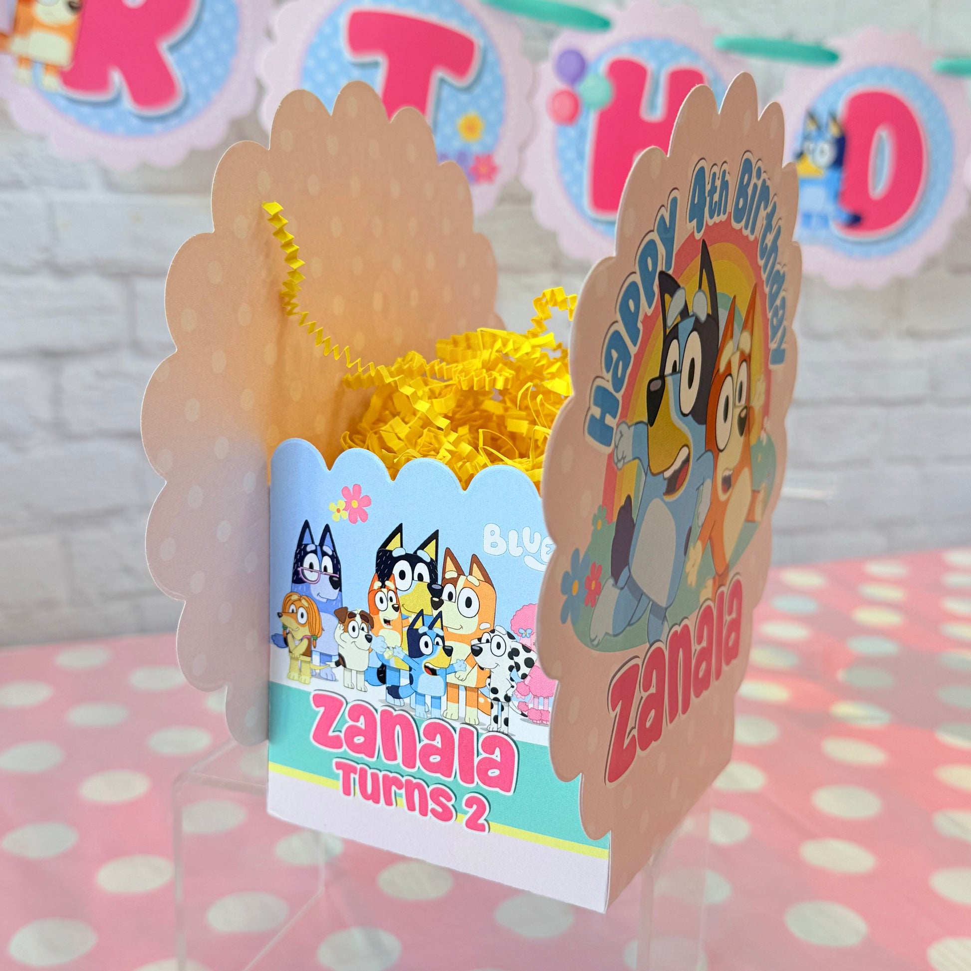 Personalized Bluey birthday party table centerpiece in pink color scheme with a rainbow and flowers for birthday girl