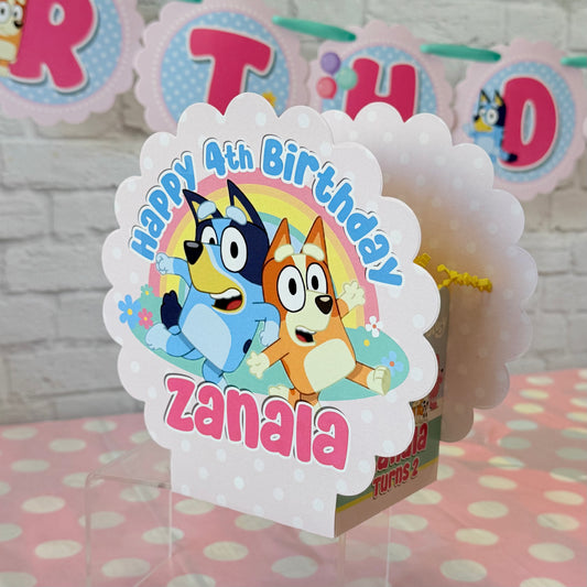 Personalized Bluey birthday party table centerpiece in pink color scheme with a rainbow and flowers for birthday girl